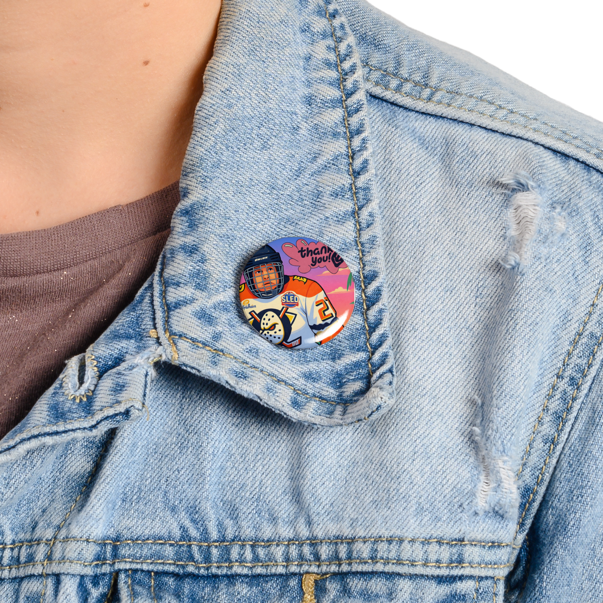 Denim jacket with a colorful button featuring an astronaut design.